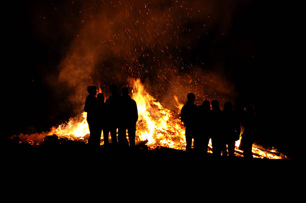 Fire with people infront a large fire in a dark room with Bonfires of Saint John in the background