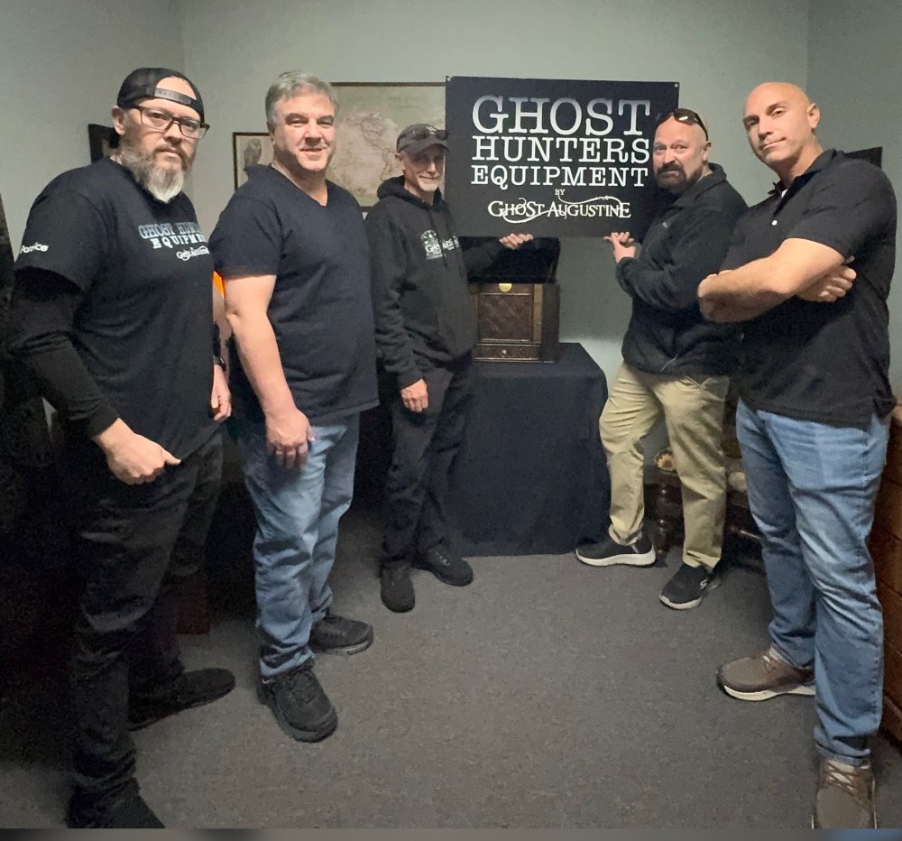 Five men stand around a sign for Ghost Hunters Equipment.